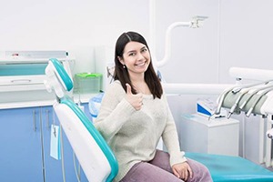 Woman in dental chair giving thumbs up